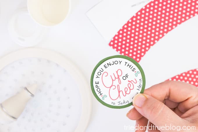 Hand holding free printable "Cup of Cheer" tag.