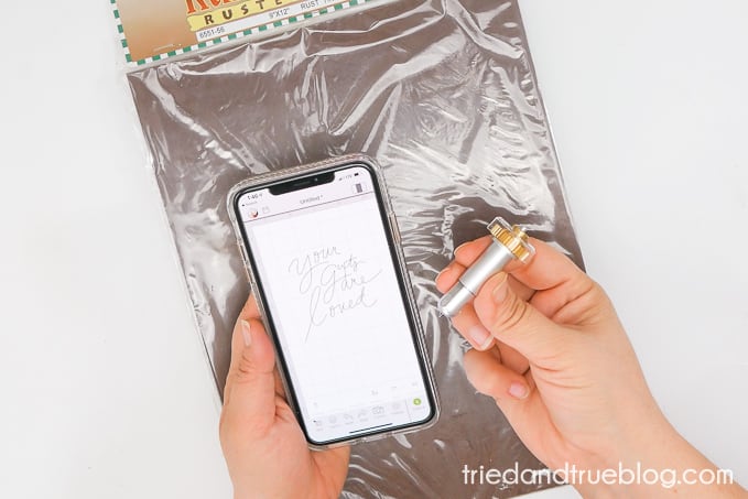 Hands holding the Engraving tip of the Cricut Maker Tools and phone with Design Space.