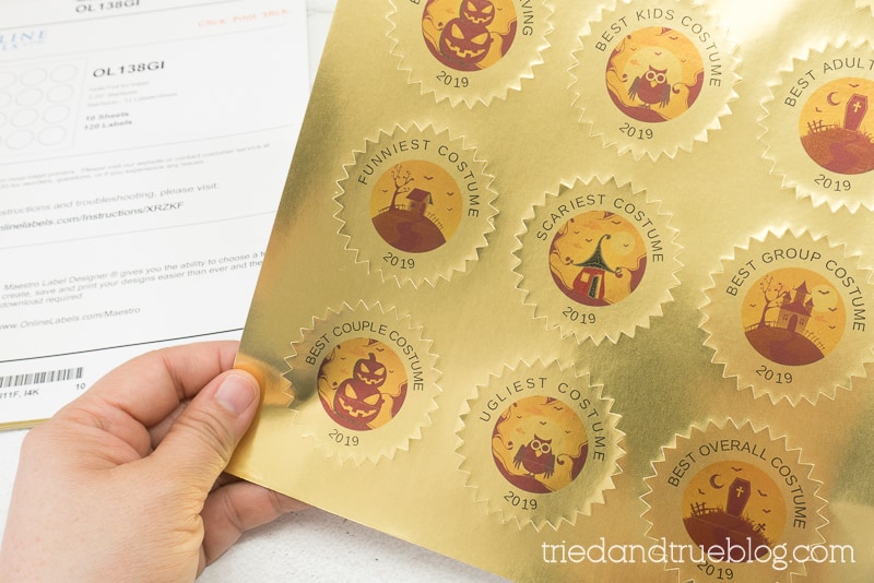 Hand holding a sheet of costume award stickers.