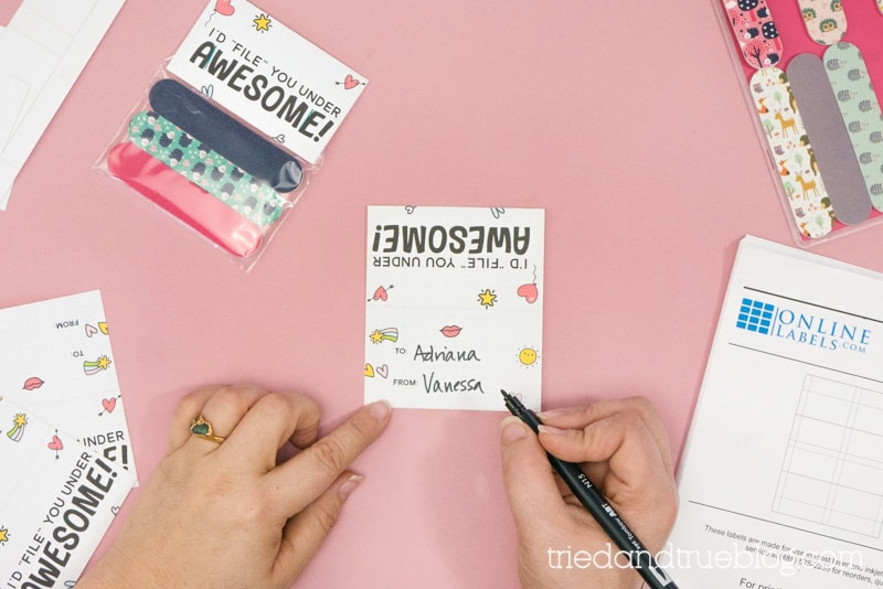 Hands writing on the printable Nail File Punny Valentine Gift label.