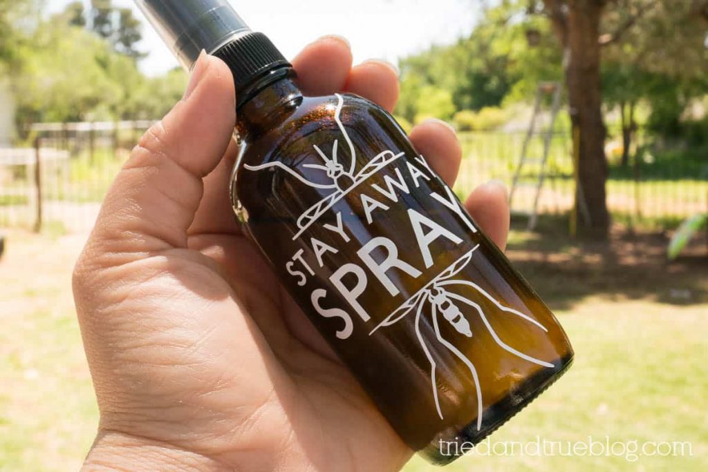 Hand holding a bottle of Homemade Mosquito Repellent.