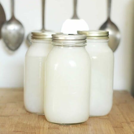 Three large mason jars on a bamboo counter filled with homemade body wash