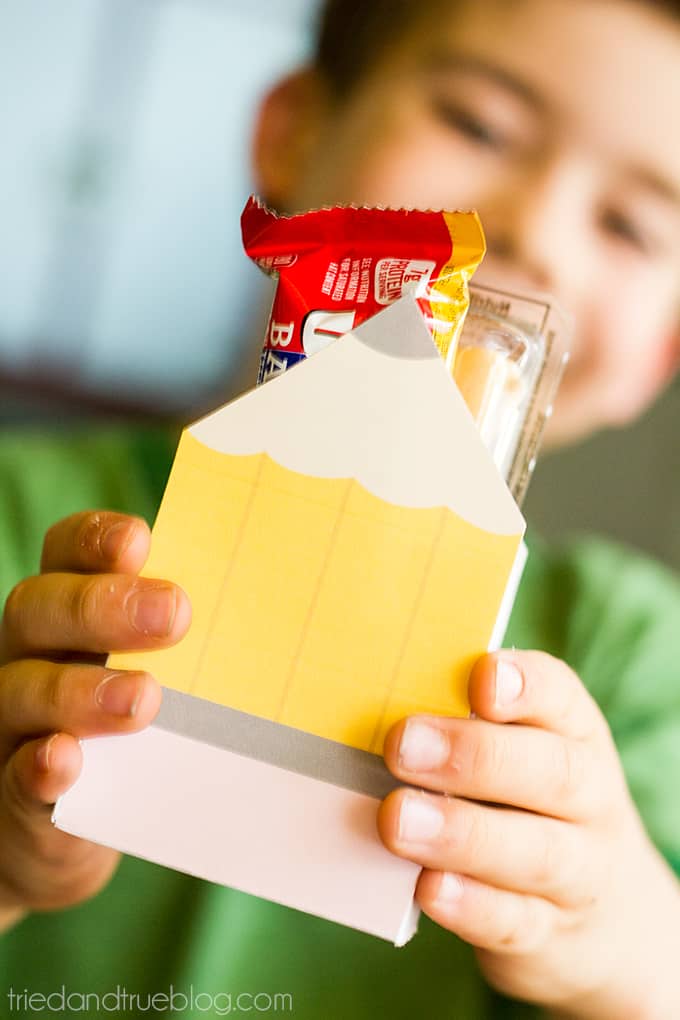 Child holding out small box filled with snacks.