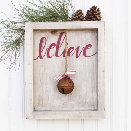 Rustic wood frame with the word "believe" and old bell.