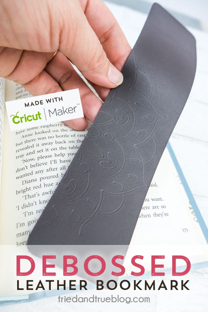 Mandala Debossed Leather Bookmark held over an open book.
