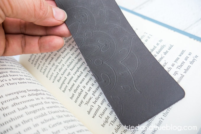 Finished Mandala Debossed Leather Bookmark held over open book.