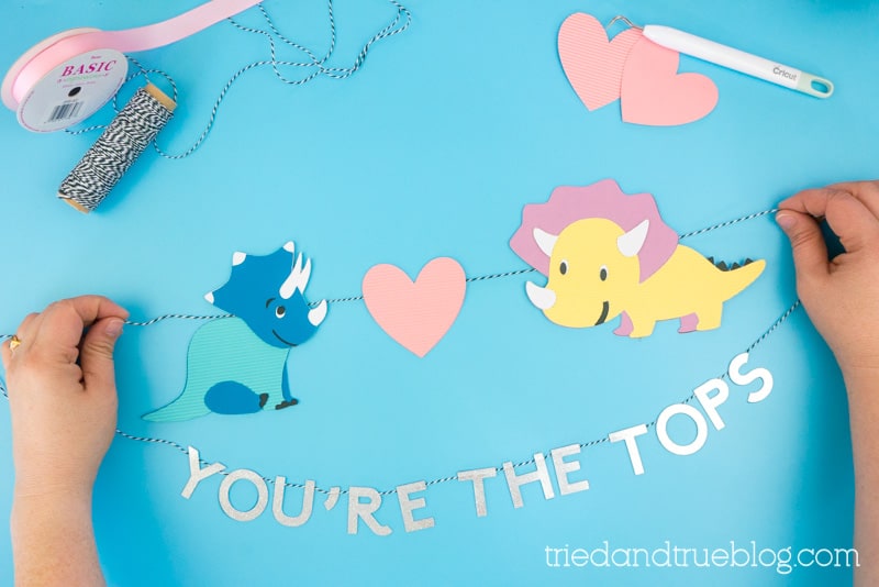 Final shot of banner made of two dinosaurs looking at each other over a heart and the words "You're the Tops."