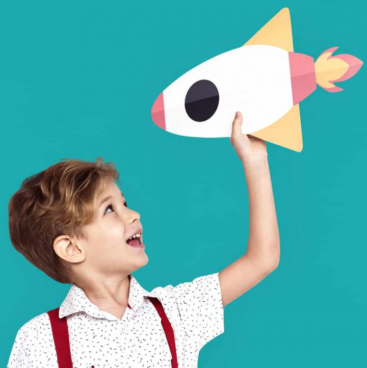 Child holding a paper rocketship.