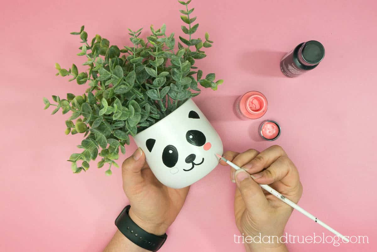 Adding paint to the front of the glazed ceramic planter.