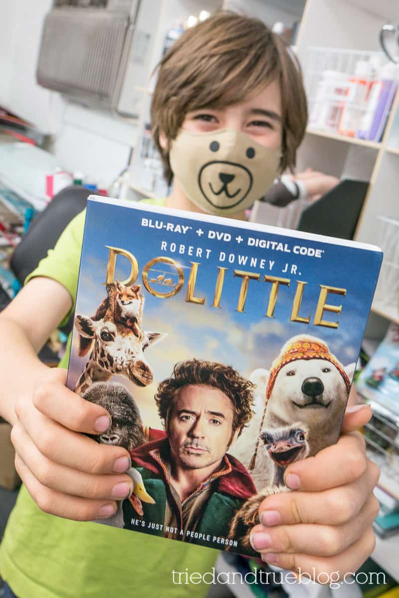 Boy holding Dolittle DVD while wearing a bear face mask.