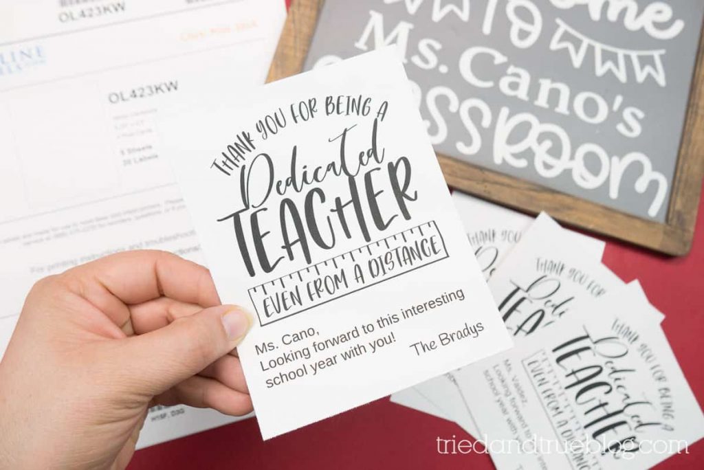 Hand holding a card that reads "Thank you for being a dedicated teacher even from a distance."