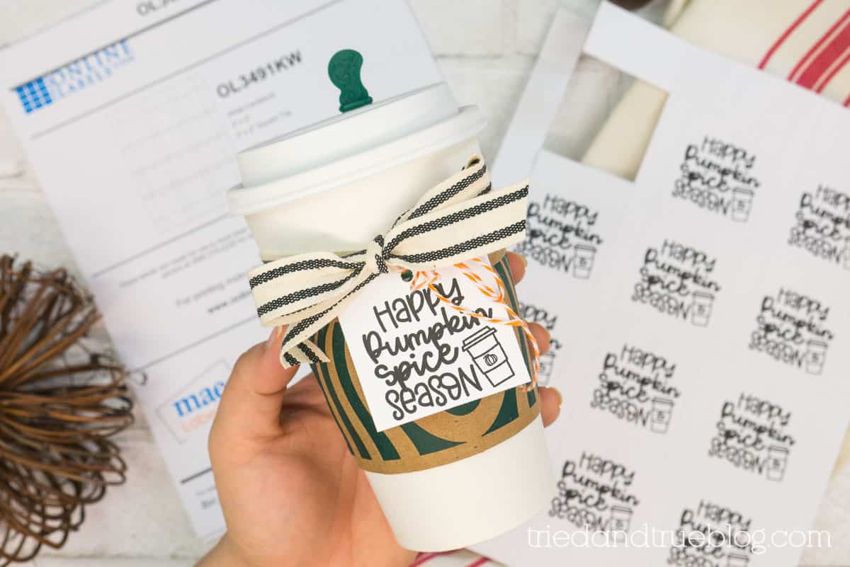 Hand holding Starbucks cup with "Happy Pumpkin Spice Season" gift tag.