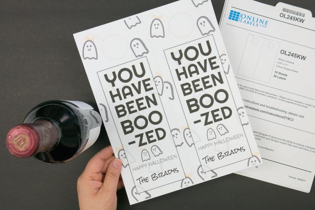Hand holding a sheet of "You Have been Boo-zed" Door Tags