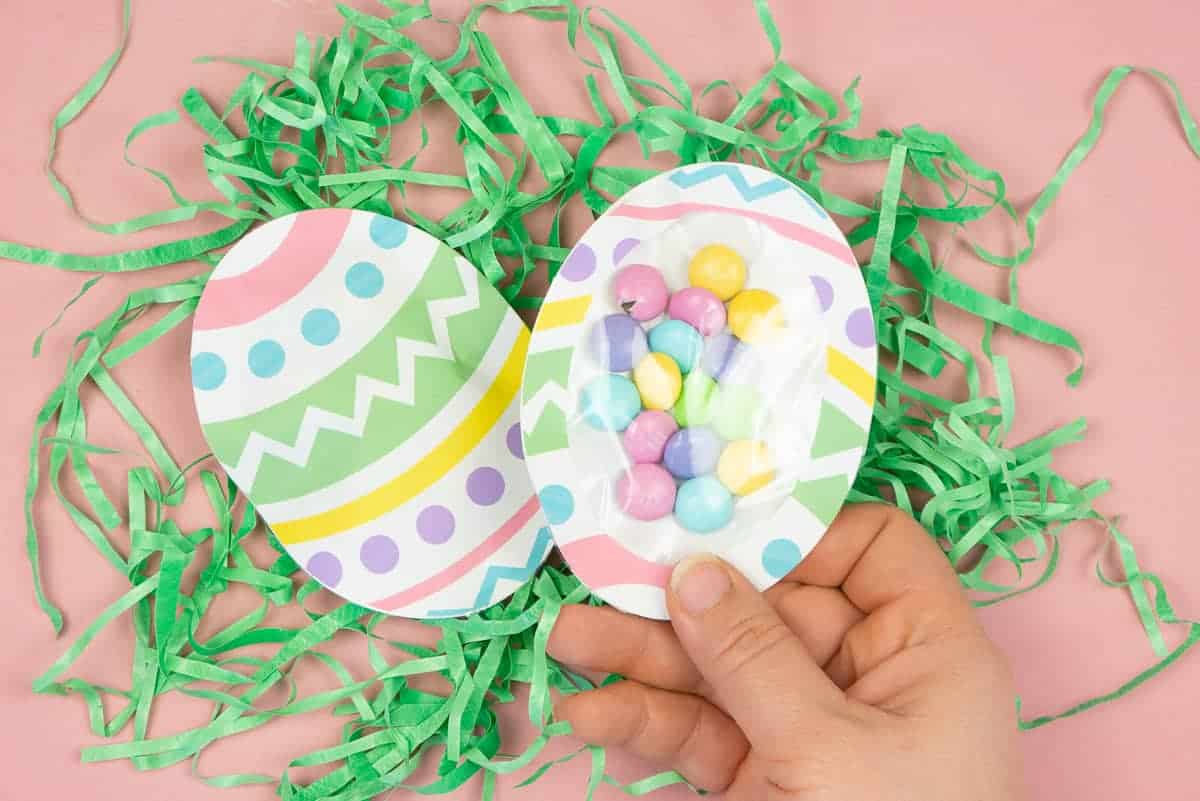 Hand holding Easter Egg Treat Pouch filled with pastel candy.