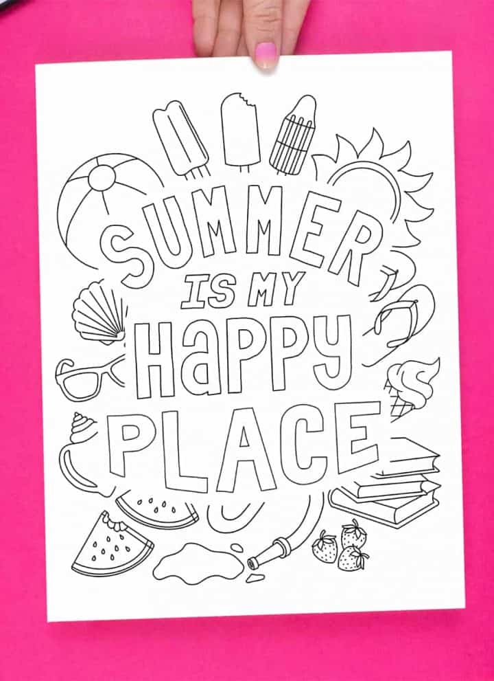 Hand holding the Summer Happy Place Coloring page on a bright pink background, surrounded by markers.