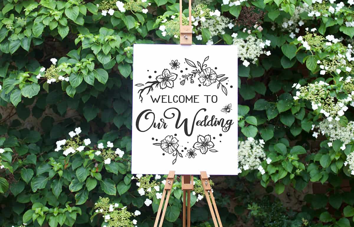 Welcome To Our Wedding free cut file on a white canvas in front of green ivy.