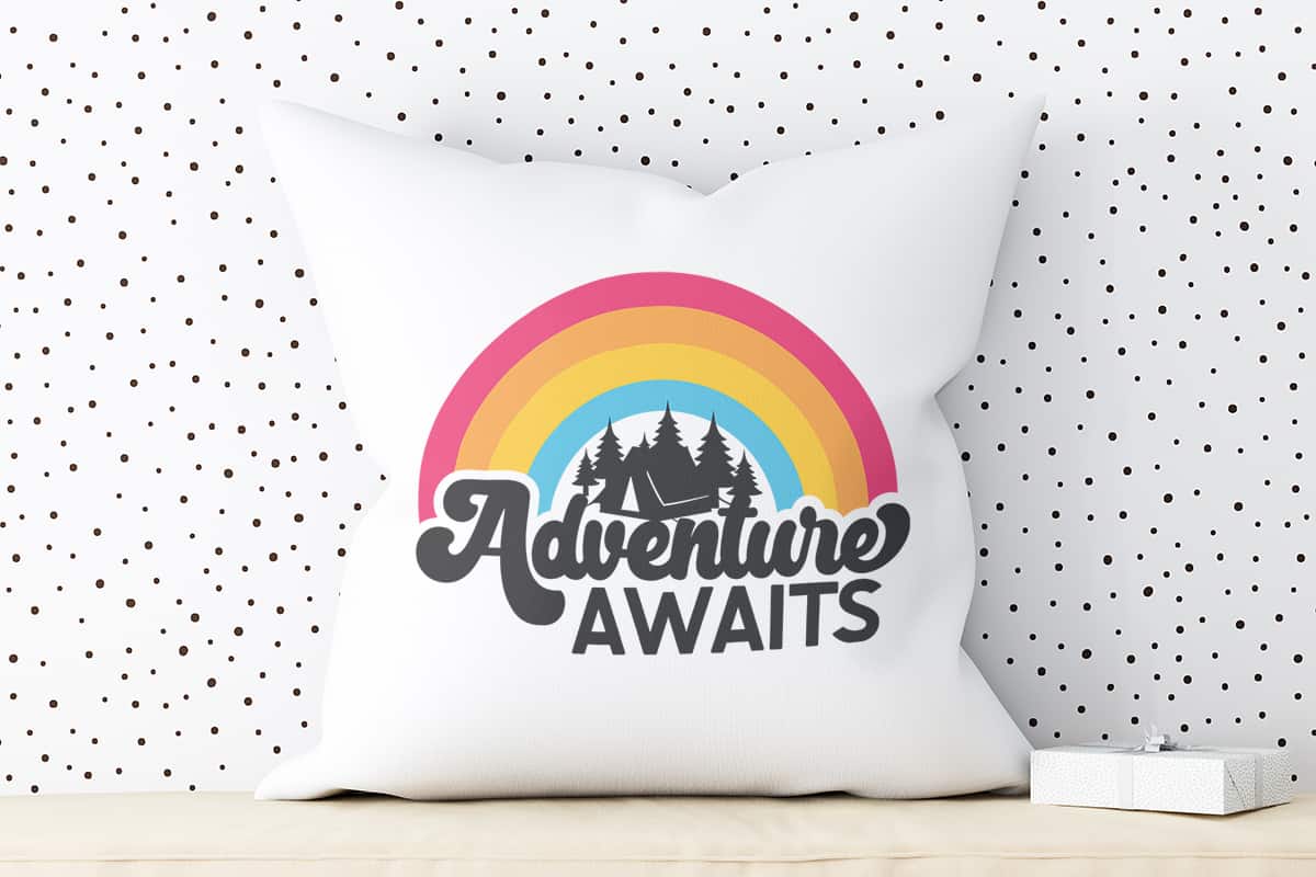 Adventure Awaits Camping SVG Free File on a pillow.