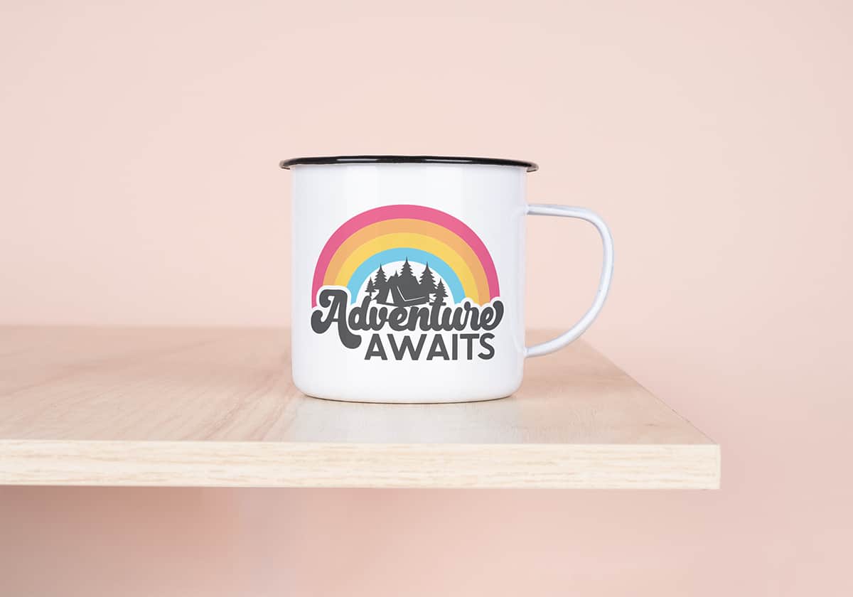 Adventure Awaits free svg file on an enamel mug on shelf on pink background. 