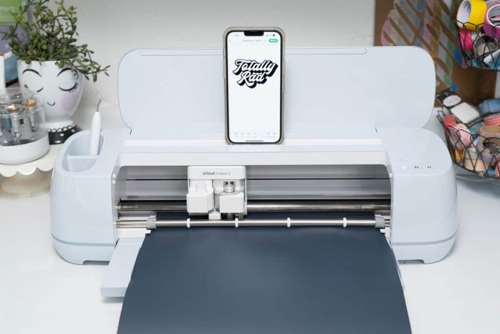 A cricut machine with an iphone attached to it.