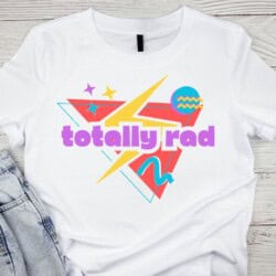 White T-shirt with retro design features "totally rad" text, geometric shapes, stars, and colorful patterns.